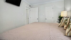 Ein Schlafzimmer mit einem Bett, zwei Türen, einem Fernseher und einer Lampe.