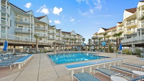 Ein Hotel mit Schwimmbad, Liegestühlen und einem überdachten Bereich mit Sonnenschirmen.