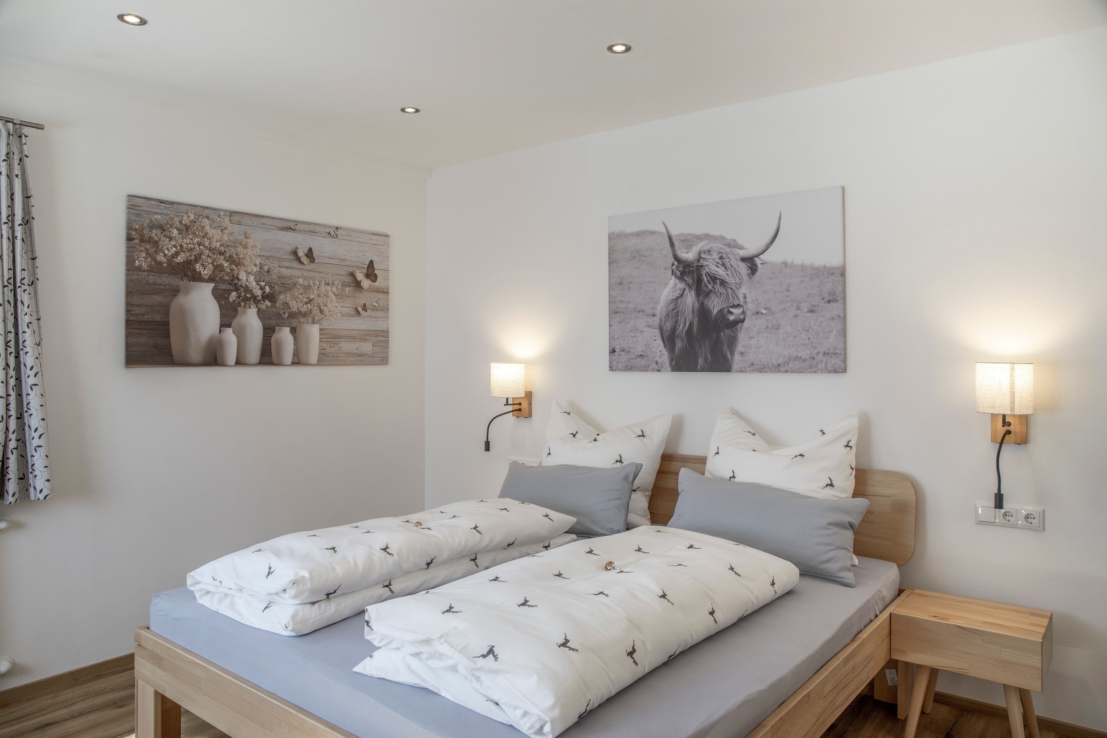 Une chambre à coucher avec un lit double, deux tables de chevet, une lampe fixée au mur et deux appliques murales.
