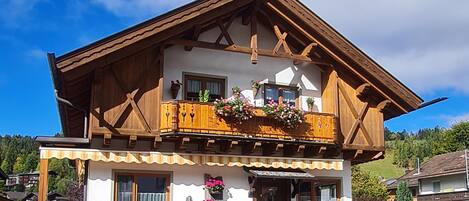 Un bâtiment à deux étages doté d’un balcon en bois, de fondations en pierre et surplombant un ciel dégagé.