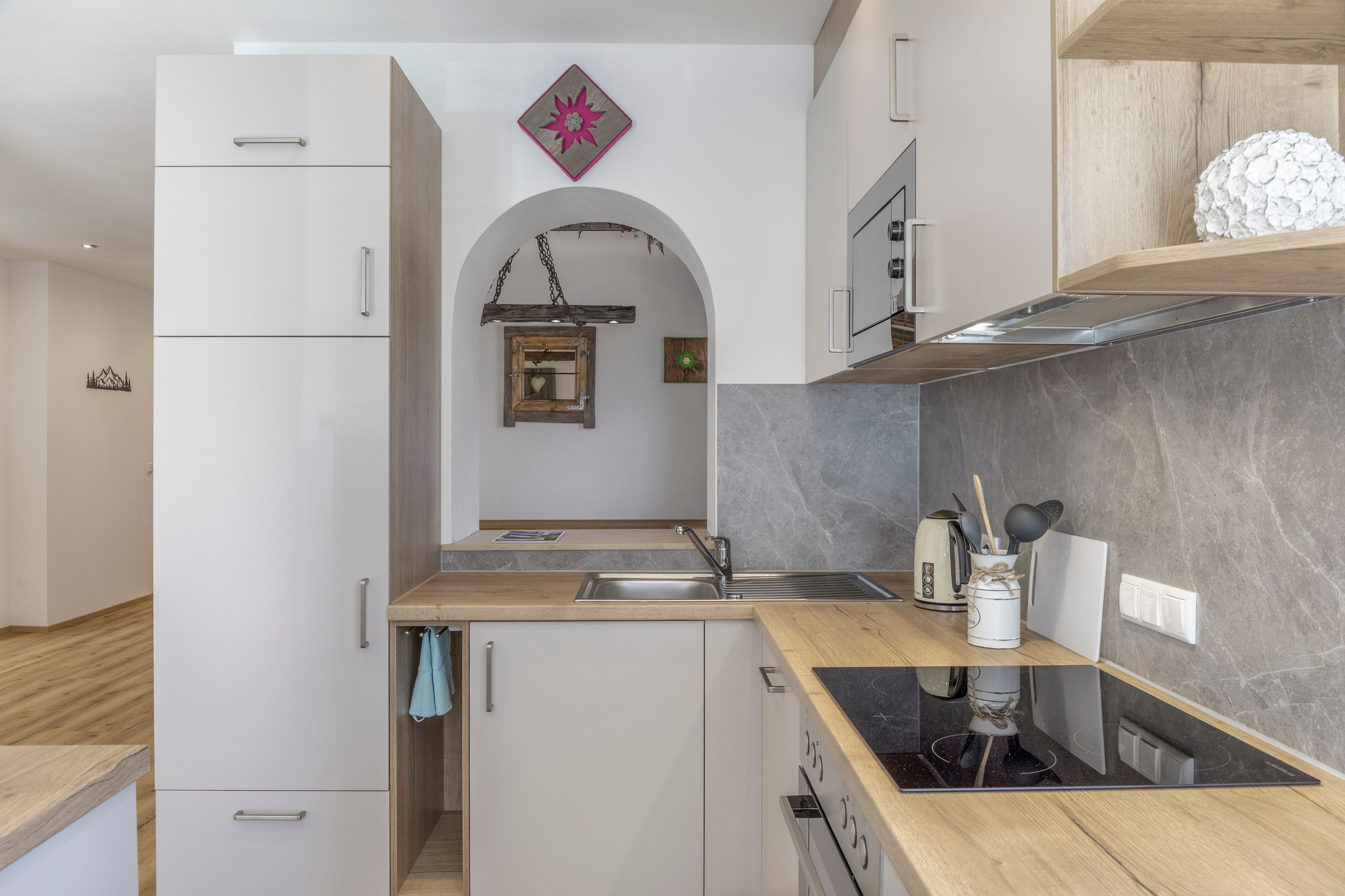 Een moderne keuken met een inbouwoven, een RVS spoelbak en een houten aanrecht.