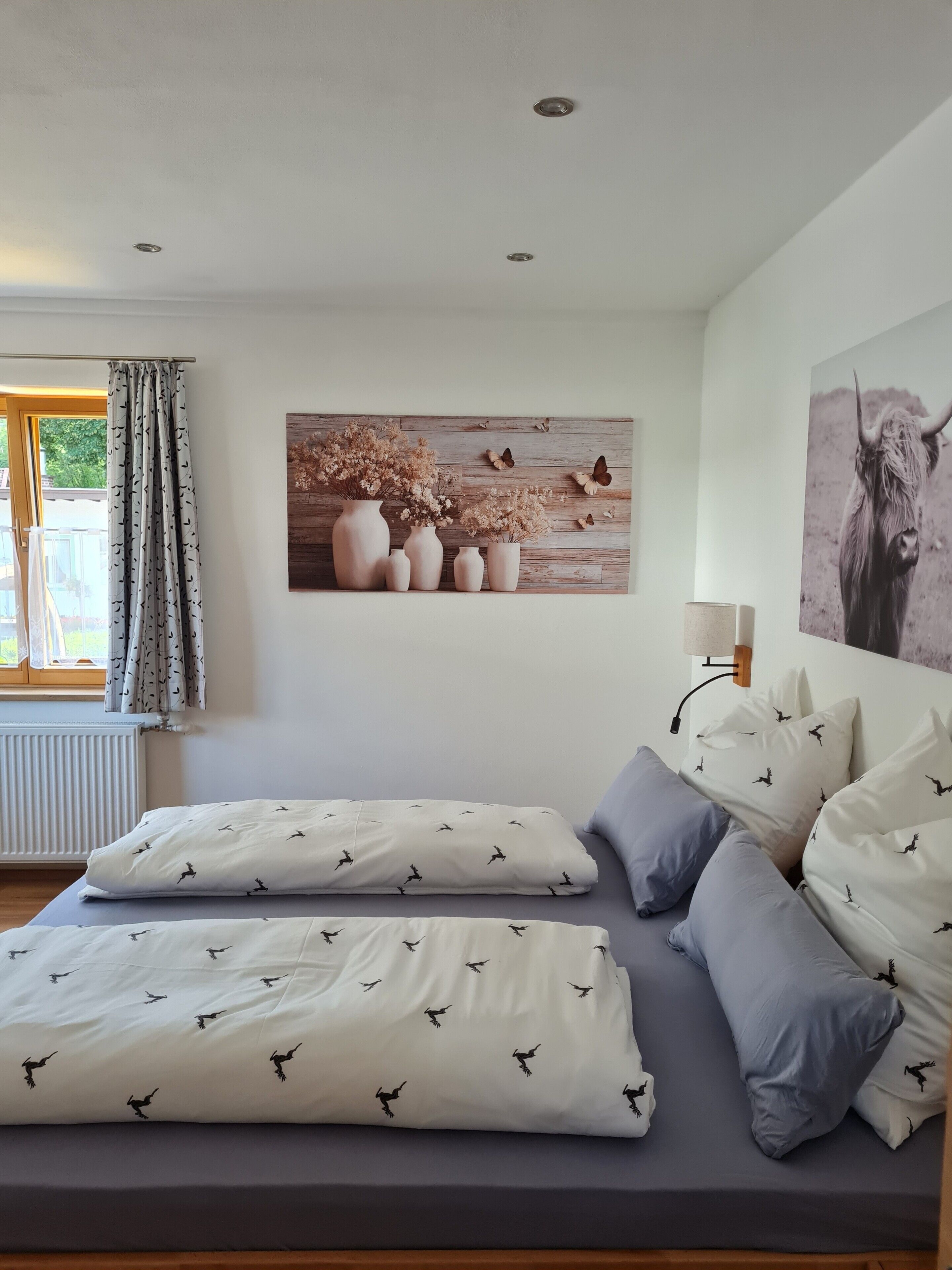 Un dormitorio con cama, almohadas, una lámpara de pared y un cuadro grande.