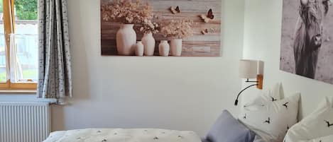 Un dormitorio con cama, almohadas, una lámpara de pared y un cuadro grande.