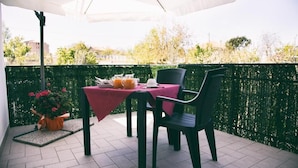 A patio with a table and chairs, a potted plant, and a decorative fence. - alba magica (Agerola)