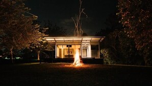 Ein modernes Gebäude mit Glasfassade, umgeben von Bäumen, in der Nacht.