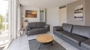 Una sala de estar moderna con un sofá gris, una mesa de centro de madera y un cuadro en la pared.