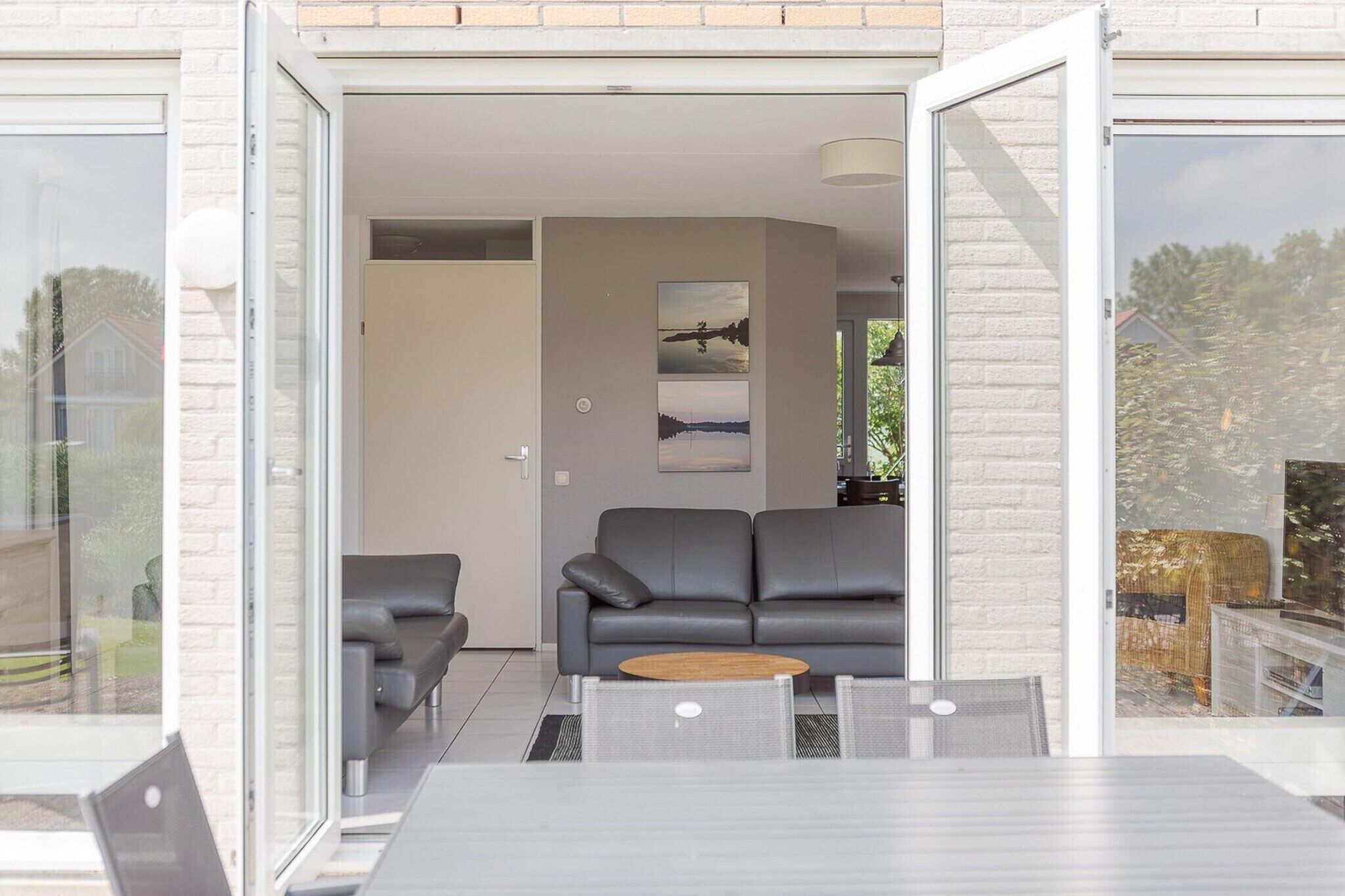 An open-plan living area with a sofa, a coffee table, and a glass door leading to an outdoor space.