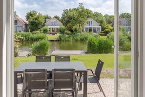 A view of a house with a pond, surrounded by greenery and other houses. - Waterfront Bungalow with Garden (Makkum)