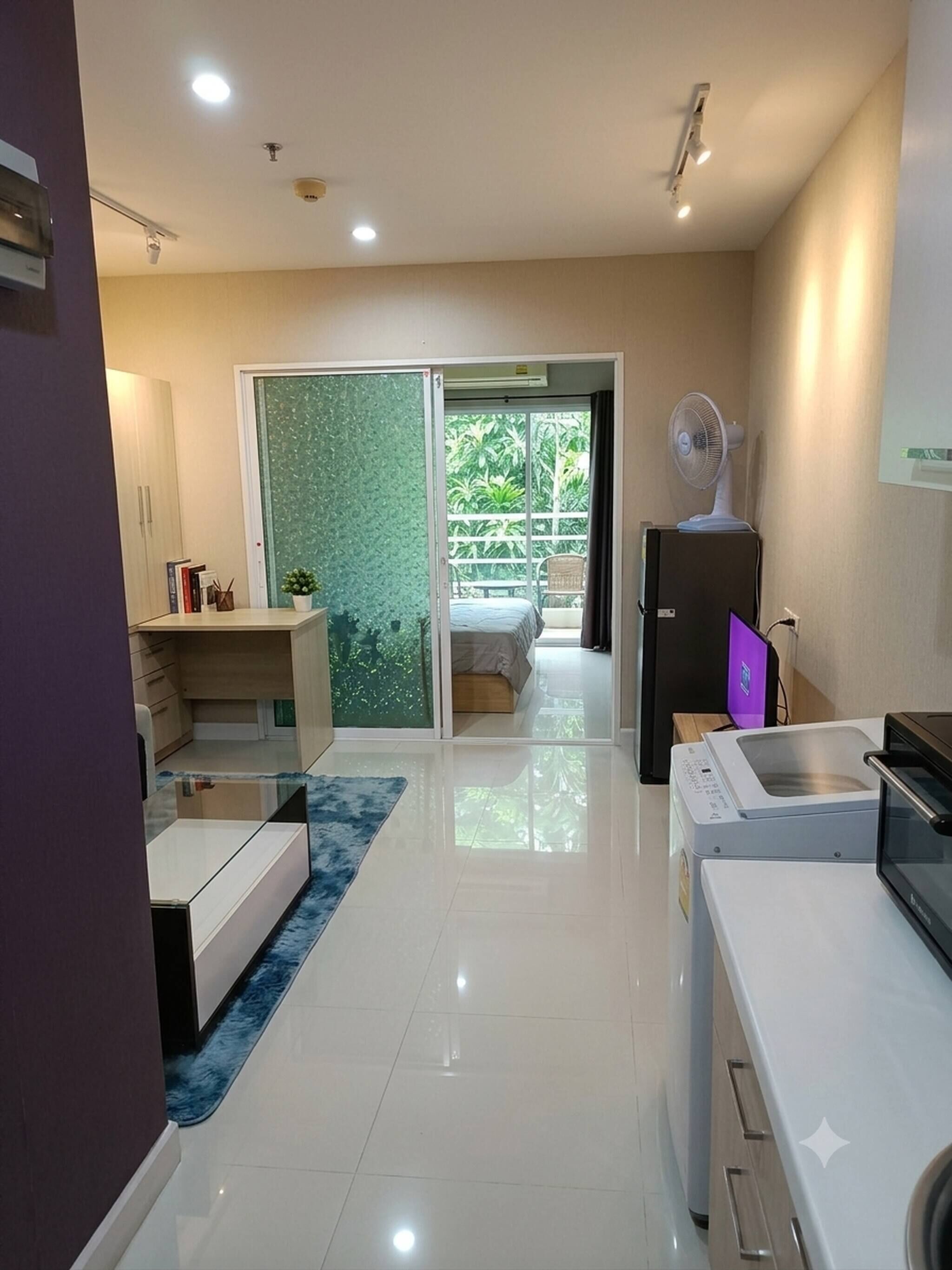 Cocina moderna con microondas, horno y ventilador. Posee un ventanal corredero que da a un balcón con cama y una silla.