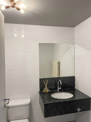 A bathroom with white tiles, a black countertop, a sink, a mirror, and a toilet. - Modern Condo Room with Private Facilities in Phasi Charoen (Phasi Charoen)