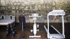 A gym with exercise equipment, a bed, and a stone wall. - Xuzhu Avatar Mountain Hideaway (Zhangjiajie)