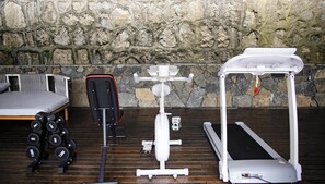 Una palestra con attrezzature per esercizi, un letto e una parete in pietra.