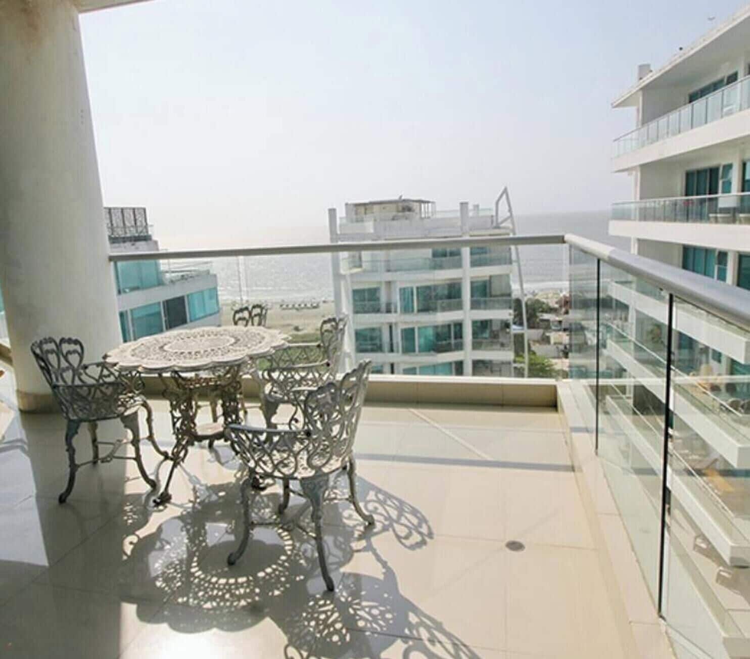 A balcony with a table and chairs, overlooking a cityscape.