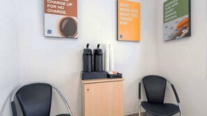 Une pièce avec deux chaises noires, un meuble en bois contenant des objets noirs et blancs, et trois affiches accrochées au mur.