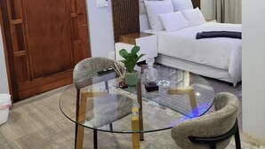 A modern hotel room with a glass table, two chairs, a sofa, and a wooden door. - Cozy and Modern Apartment Rental in Akasia, Pretoria (Akasia)