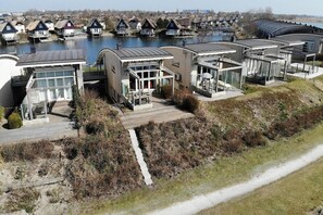 A modern hotel with large windows, a covered outdoor area, and a view of a body of water.