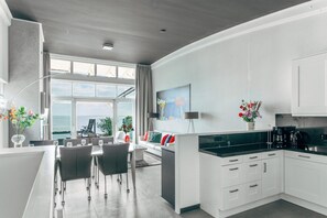 A modern kitchen with white cabinets, a dining area with a table and chairs, and a large window with a view of the sea. - Deluxe Dike Villa with Sauna for 6 (Makkum)