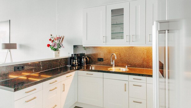 A modern kitchen with white cabinets, a granite countertop, and a stainless steel sink. - Deluxe Dike Villa with Sauna for 6 (Makkum)