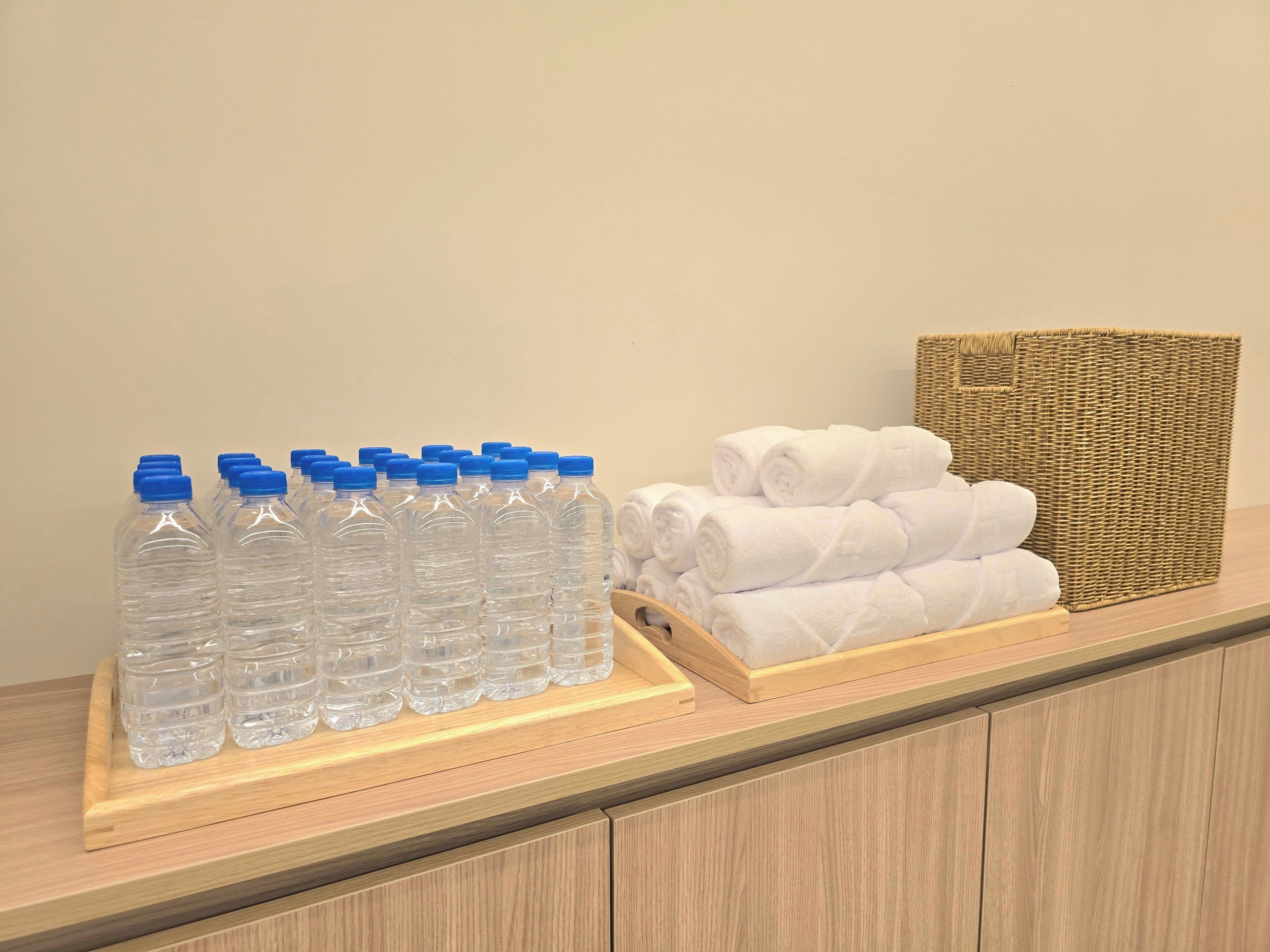 Un estante de madera con botellas de agua transparentes y toallas blancas dobladas con cuidado.