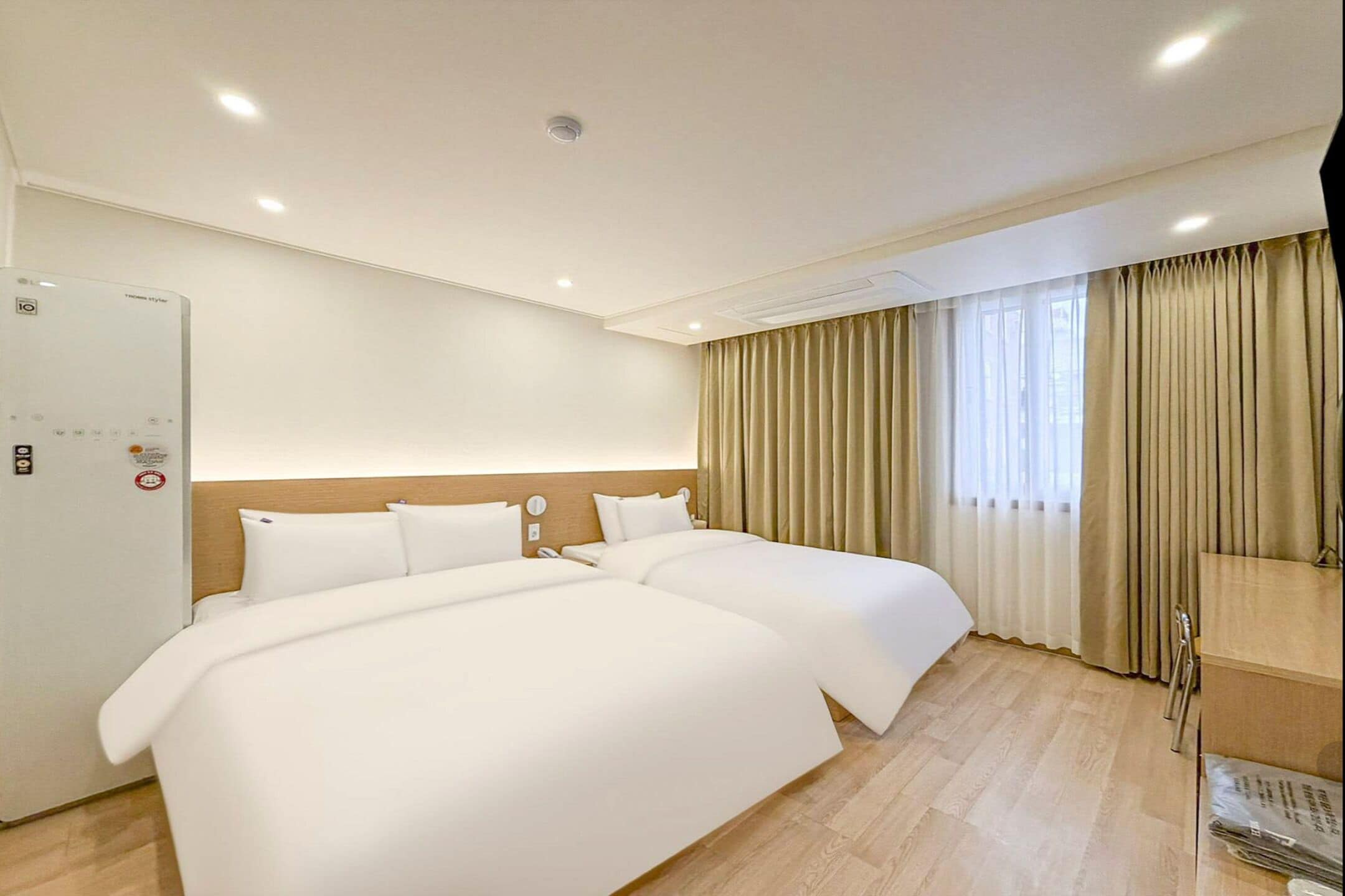 Ein Hotelzimmer mit einem großen Bett, einem Nachttisch, einem Kleiderschrank und einem Fenster mit Vorhängen.