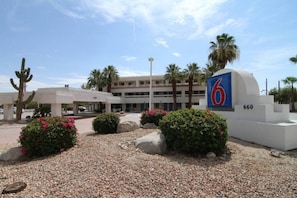 A hotel entrance with a large sign, palm trees, and a parking area. - 1 Queen Bed | Micfridge (Palm Springs)