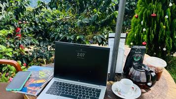 Una computadora portátil sobre una mesa de madera, con una taza de café, un paquete de café y un teléfono inteligente a un lado.