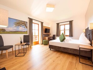 Ein Hotelzimmer mit Bett, Schreibtisch, Stuhl, Fernseher und einem Bild an der Wand.