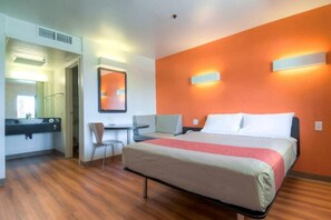 A hotel room with a bed, a desk, a chair, and a mirror. - 1 Queen Bed|Palm Springs, CA (Palm Springs)