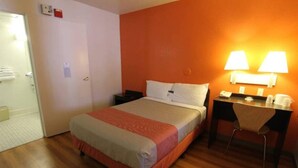 A hotel room with a bed, bedside table, desk, chair, and a door. - 1 Queen Bed|Palm Springs, CA (Palm Springs)