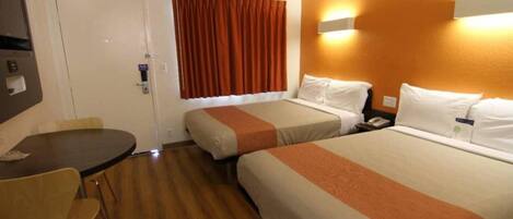 A hotel room with two beds, a desk, and a chair.