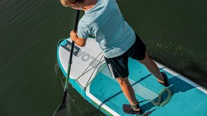 A person standing on a paddleboard in a body of water. - Lakeview Apartment with Dual Balconies (Makkum)