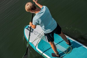Una persona de pie en una tabla de remo sobre el agua.