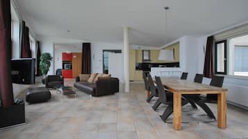 Uma sala de estar moderna com sofá, mesa de centro e mesa de jantar com cadeiras.