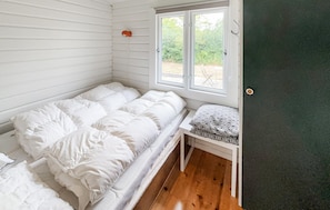 A single bed with white bedding in a room with wooden flooring and a window with a view of greenery. - 3 bedroom nice home in Skjern (Skjern)