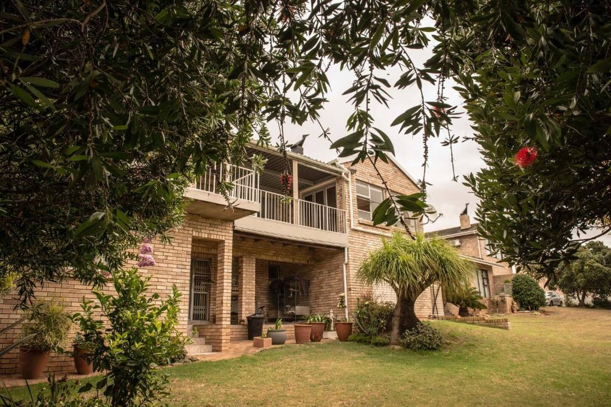 A two-story house with a balcony, brick exterior, and a well-maintained lawn.