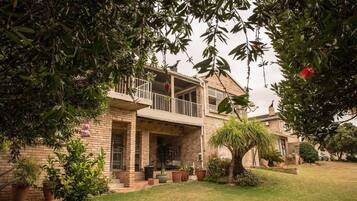 Une maison à deux étages dotée d’un balcon, d’une façade en briques et d’une pelouse bien entretenue.