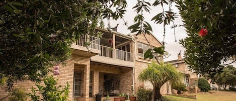 A two-story house with a balcony, brick exterior, and a well-maintained lawn.