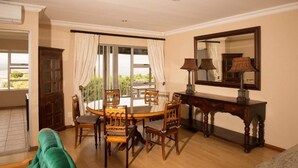 Un coin repas comprenant une table ronde, des chaises, une console en bois et un grand miroir.