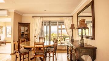 Un coin repas comprenant une table ronde, des chaises, un buffet et un grand miroir.