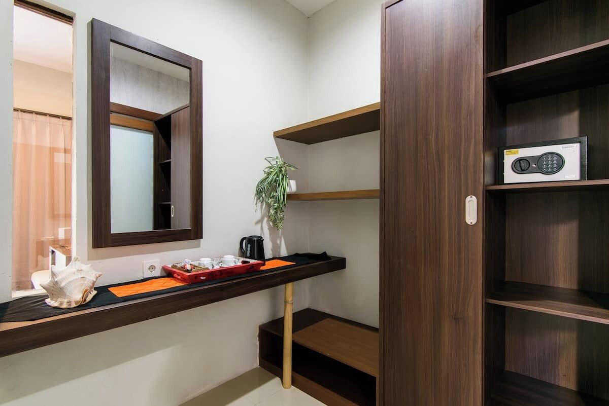 A room with a wooden shelf, a mirror, a plant, and a radio.