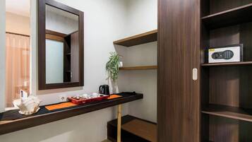 A room with a wooden shelf, a mirror, a plant, and a radio.