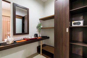A room with a wooden shelf, a mirror, a plant, and a radio.