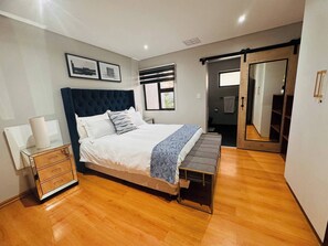 Une chambre moderne avec un grand lit, des tables de chevet, un banc et une armoire.