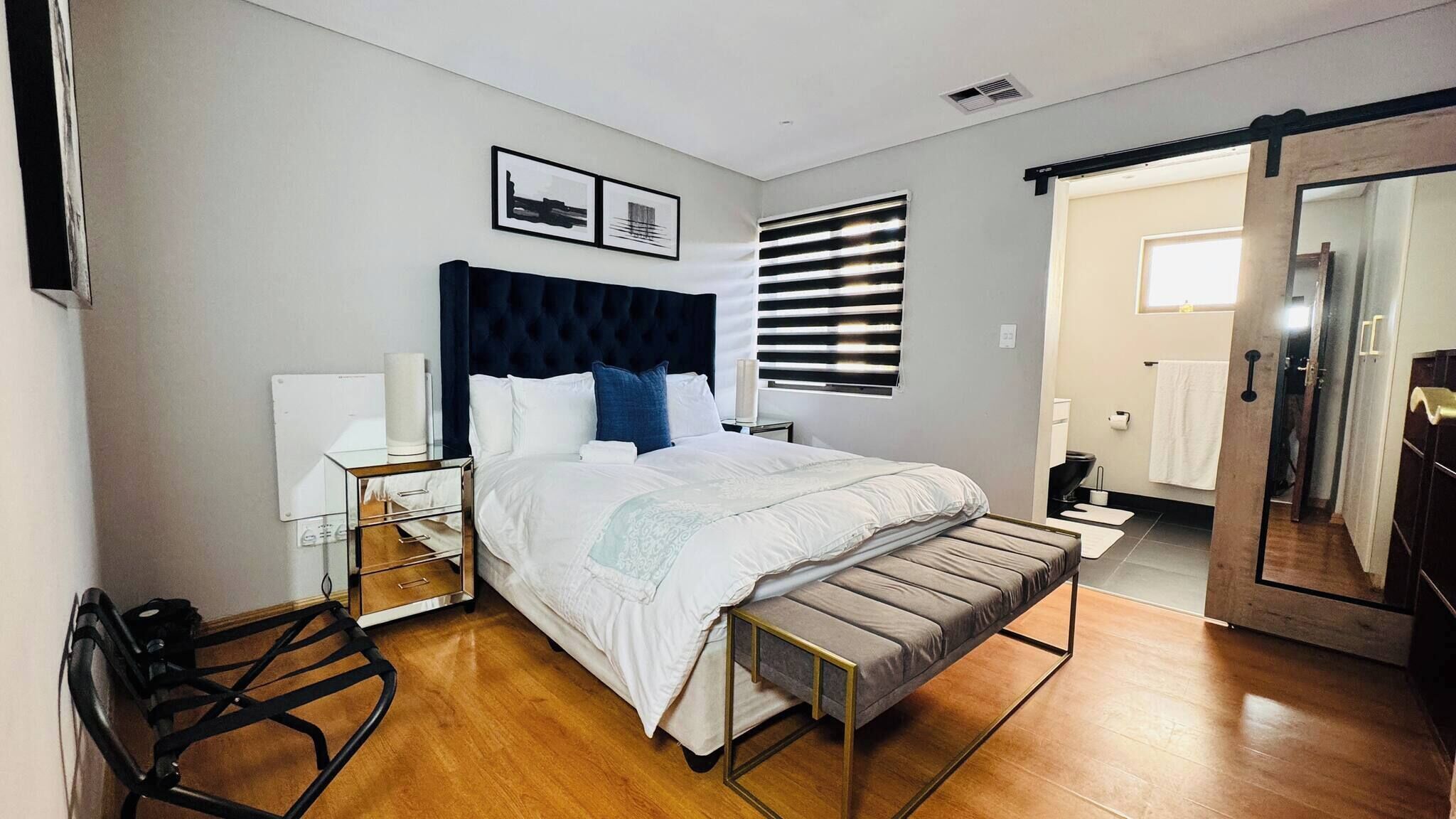 A modern bedroom with a large bed, bedside tables, a chair, and a wardrobe.