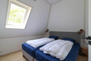 Un dormitorio con dos camas, una ventana y una lámpara de noche.