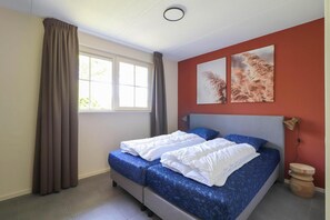 A bedroom with a bed, curtains, a window, and wall art. - Luxury Beach Villa with Hot Tub (Makkum)