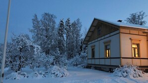 Ett snötäckt landskap med en byggnad som har ett sluttande tak och en balkong.