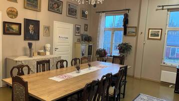 A dining room with a wooden table, chairs, a chandelier, and various framed pictures on the walls.