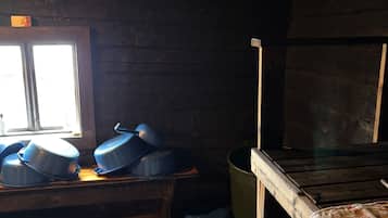 Un interior rústico de madera con un banco, una ventana y una mesa con recipientes azules.