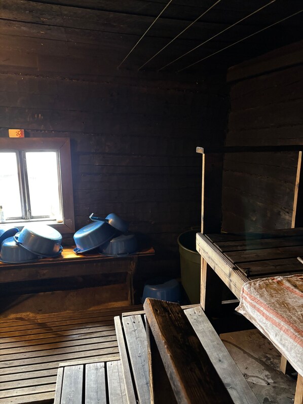 Un intérieur rustique en bois, avec un banc, une fenêtre et une table sur laquelle se trouvent des récipients bleus.